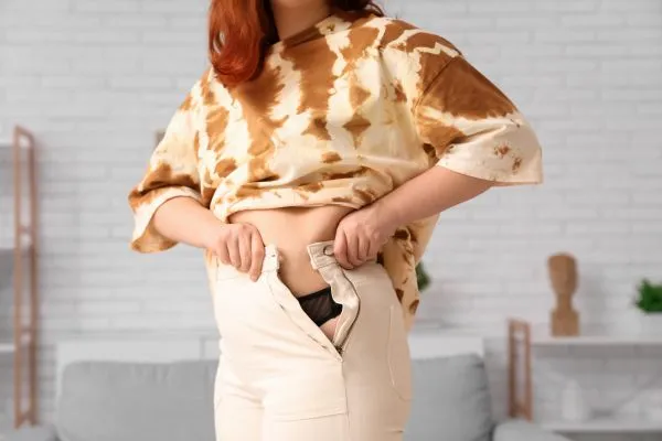 Image of woman trying to do her trousers up after pregnancy weight gain Solihull